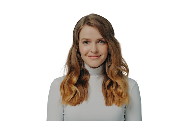 Beautiful dreamy young woman with perfect wavy styled hair in white turtleneck smiling at camera