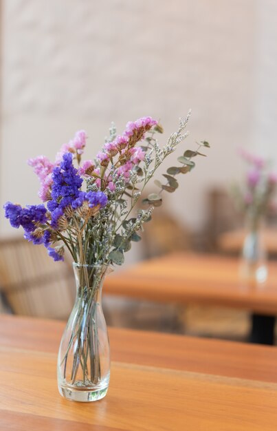 Beautiful dried flowers in glass vase on wood table,restaurant interior