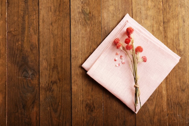 Beautiful dry flowers on napkin on wooden background