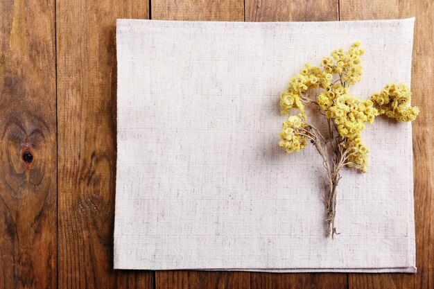 Beautiful dry flowers on napkin on wooden background