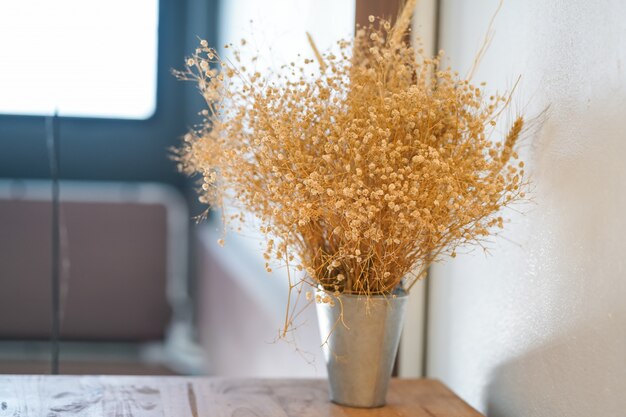 Bei fiori dell'erba asciutta disposti su una tavola di legno nel salone.