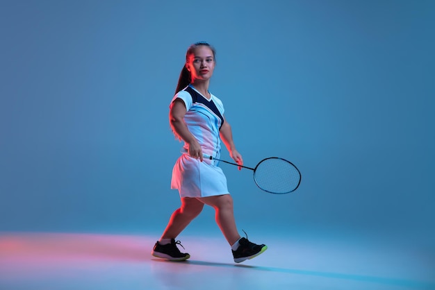 Beautiful dwarf woman practicing in badminton isolated on blue in neon light