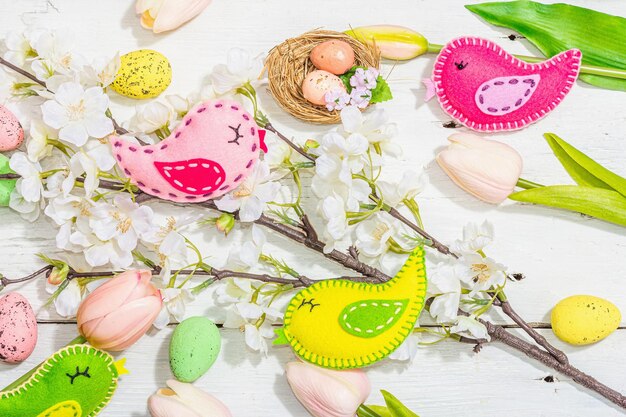 Beautiful Easter background with traditional decor Flowers decorative eggs birds and rabbits Modern hard light dark shadow white boards flat lay top view