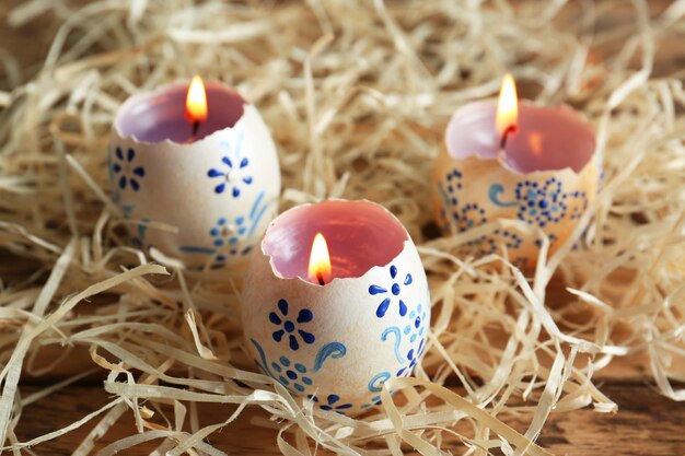 Photo beautiful easter candles with floral ornament in decorative nest closeup