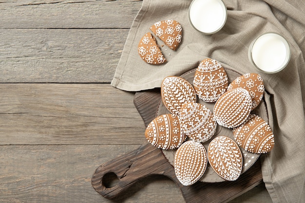 Beautiful easter cookies on a plate, a glass of milk. On old wooden background