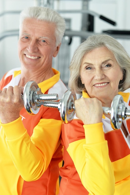 Beautiful elderly couple in a gym with dumbbells