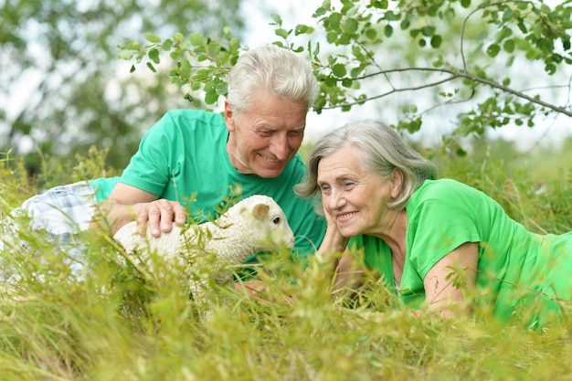 Фото Красивая пожилая пара в поле с игрушечной овечкой