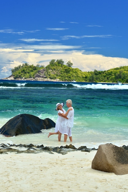 Beautiful elderly couple standing on the beach embracing