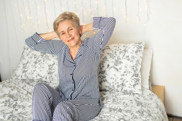 Beautiful elderly woman in pajamas in bed