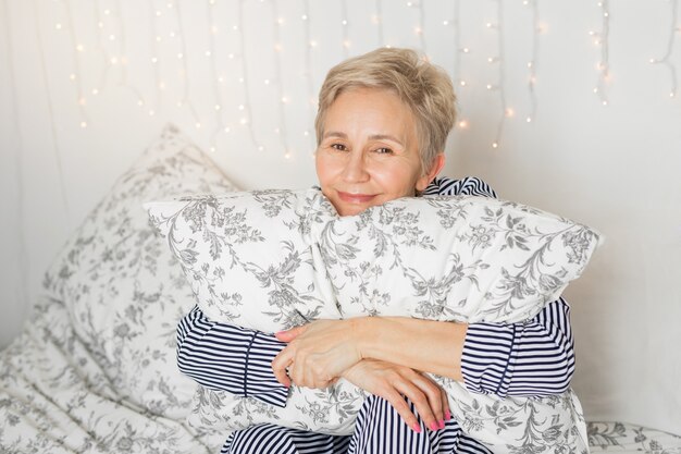 Beautiful elderly woman in pajamas in bed