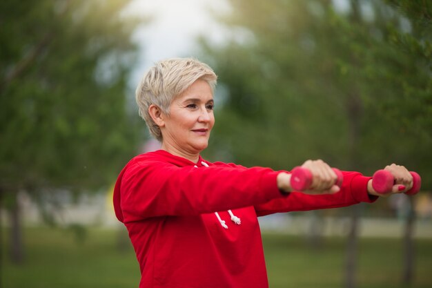 beautiful elderly woman with short haircut goes in for sports in the park