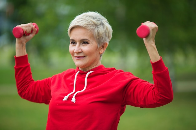 beautiful elderly woman with short haircut goes in for sports in the park