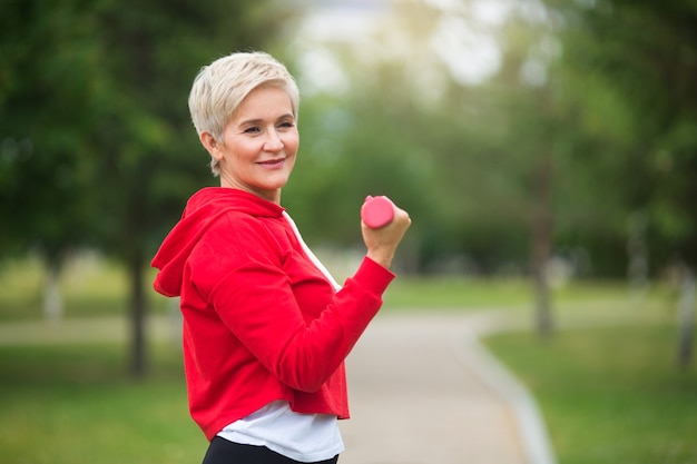 Foto bella donna anziana con taglio di capelli corto va a fare sport nel parco