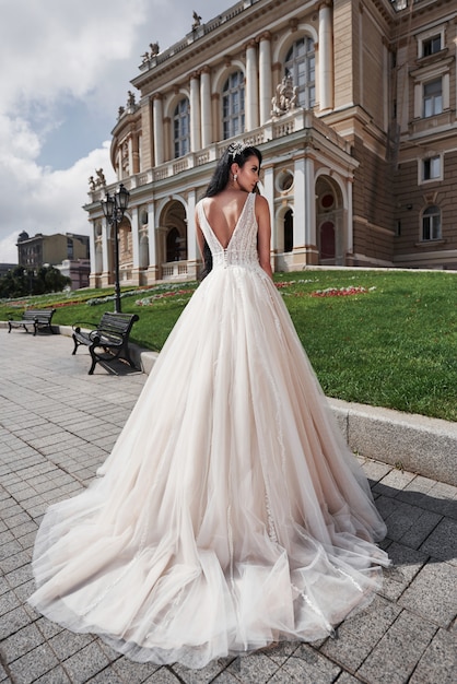 Beautiful, elegant bride with a perfect wedding dress, poses around beautiful architecture