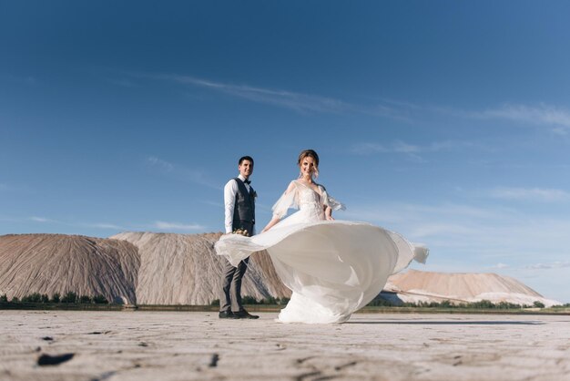 塩の山と採石場の美しい自然の背景に恋をしている新婚夫婦の美しいエレガントなカップル