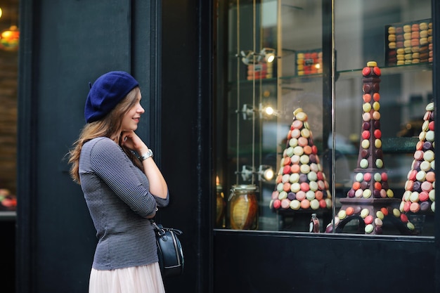 Foto bella ragazza elegante a parigi una bellezza in un berretto blu sullo sfondo di un caffè parigino