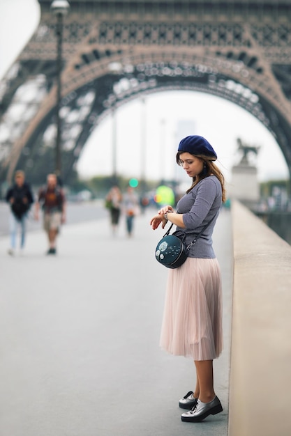 Foto bella ragazza elegante a parigi una bellezza in un berretto blu sullo sfondo della senna