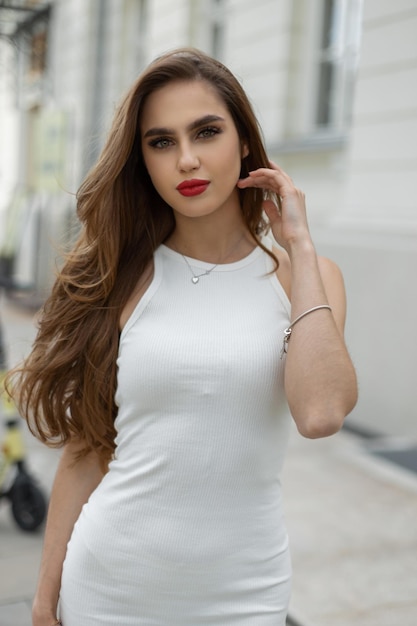 Beautiful elegant vogue girl model brunette in a fashionable white dress walks in the city