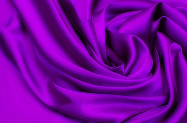 Beautiful elegant wavy violet purple satin silk luxury cloth fabric texture with violet background design.