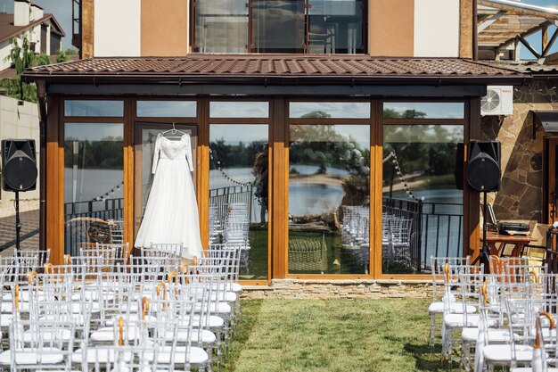 Beautiful and elegant white wedding dress hanging on the glass facade of the building.