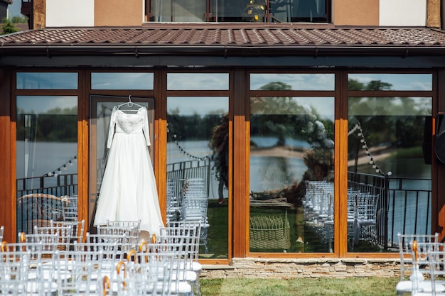 Beautiful and elegant white wedding dress hanging on the glass facade of the building.