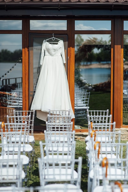 Beautiful and elegant white wedding dress hanging on the glass facade of the building.