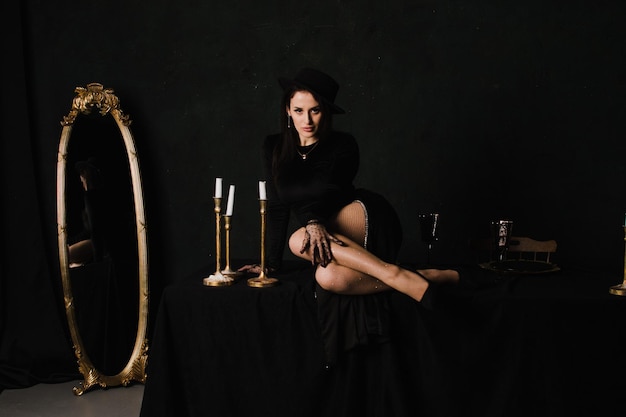 Beautiful elegant woman in gloves and a dress sits on a table on a black background