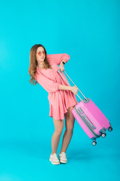 Beautiful elegant woman in a pink dress with a pink big suitcase for travel