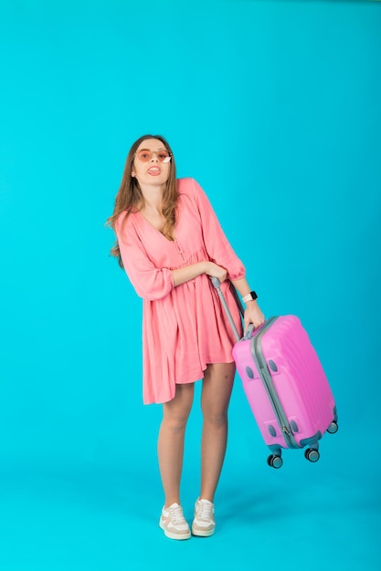 Beautiful elegant woman in a pink dress with a pink big suitcase for travel