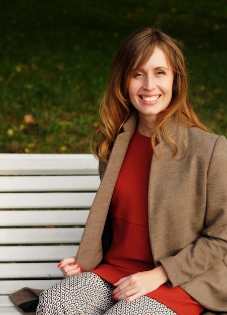 Beautiful elegant woman standing in a park in autumn