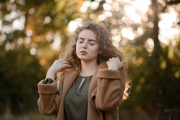 Beautiful elegant woman standing in a park in autumn