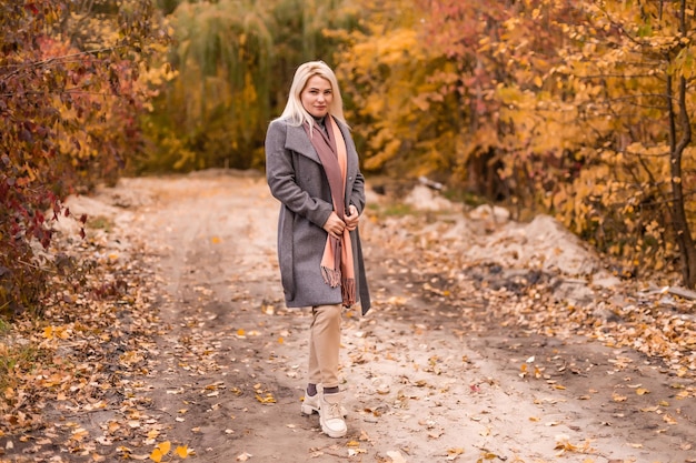 Beautiful elegant woman standing in a park in autumn