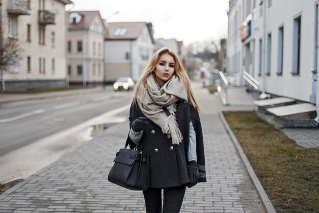 Beautiful elegant young woman in an autumn coat with a scarf