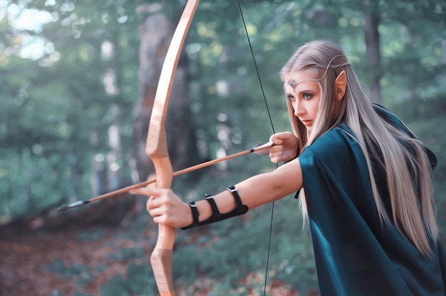 Beautiful elf woman archer in the forest hunting with a bow