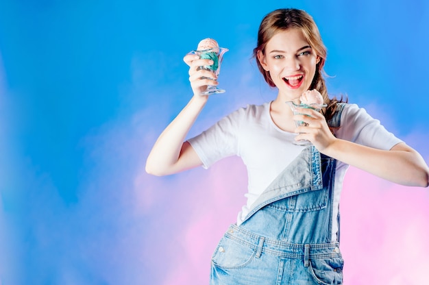 Beautiful emotional girl on a blue  holds in her hands a delicious pink ice cream. sweet sale , sale