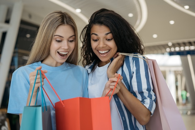 Belle donne emotive che tengono i sacchetti della spesa nel centro commerciale. grande concetto di vendita