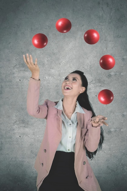 Beautiful entrepreneur juggling red balls