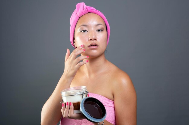 Beautiful ethnic Chinese woman taking care of her face with face cream