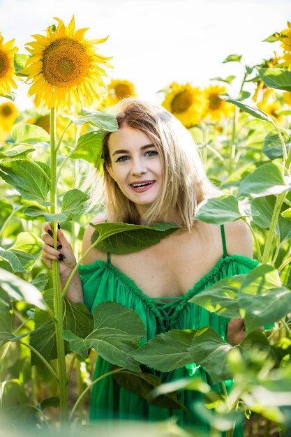 Beautiful european girl in a green dress  on nature with sunflowers