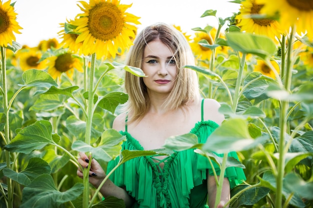 해바라기와 자연에 녹색 드레스에 아름 다운 유럽 소녀