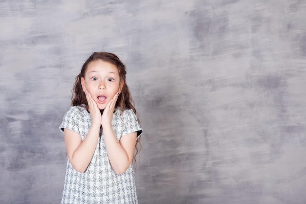 A beautiful European girl is surprised Portrait of a 7yearold child on a white background Children's emotions gestures