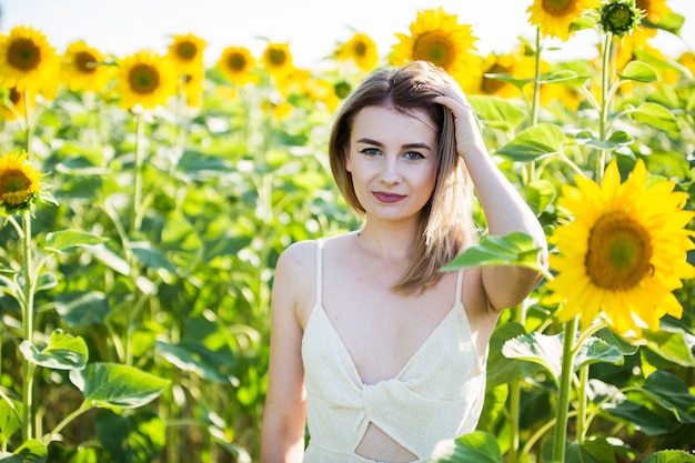 Beautiful european girl in a white dress  on nature with sunflowers