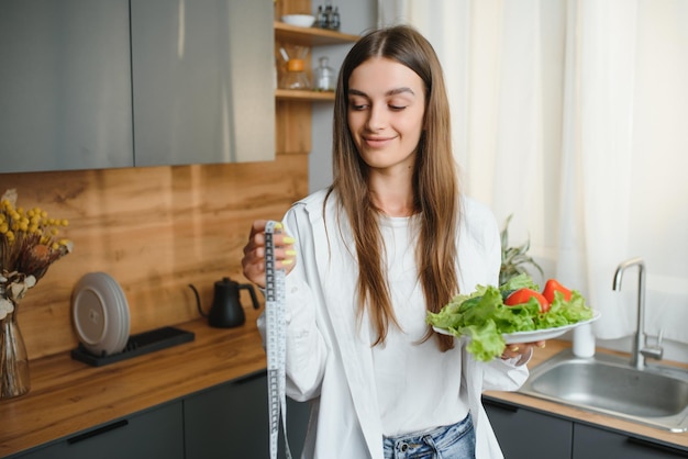 Beautiful European woman preparing a toast of vegetables and microgreens Nutritionist teaches healthy eating The vegetarian diet raw food Dinner of modern people Cooking sandwich Girl happy cook