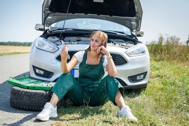 Красивая европейская женщина ремонтирует машину на дороге
