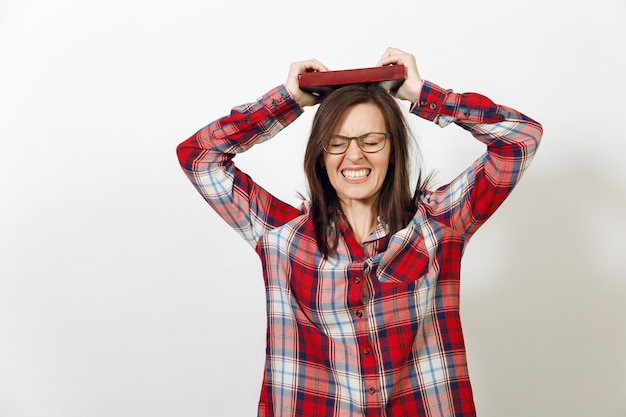 Una bella giovane donna europea dai capelli castani con gli occhiali per la vista con una pelle sana e pulita vestita con una camicia casual a quadri rossa, in piedi con il libro su uno sfondo bianco. leggere e studiare il concetto