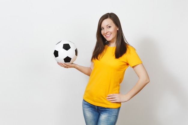 Beautiful european young cheerful happy woman, football fan or\
player in yellow uniform holding soccer ball isolated on white\
background. sport, play football, health, healthy lifestyle\
concept.