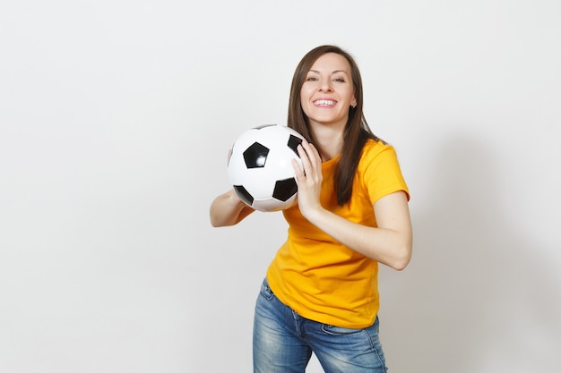 Beautiful european young cheerful happy woman, football fan or\
player in yellow uniform holding soccer ball isolated on white\
background. sport, play football, health, healthy lifestyle\
concept.