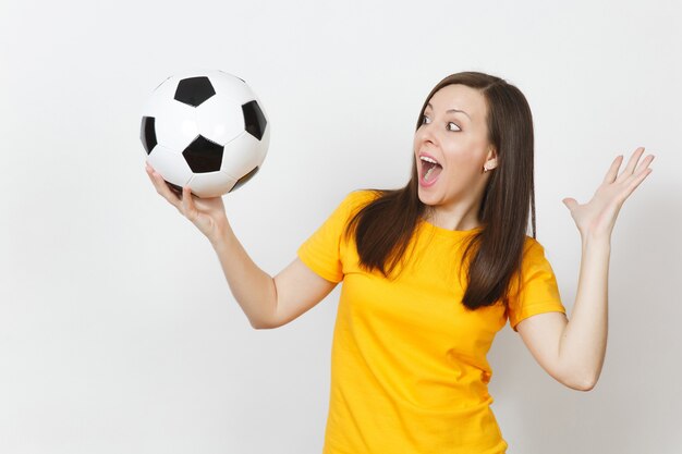 Beautiful european young cheerful happy woman, football fan or\
player in yellow uniform holding soccer ball isolated on white\
background. sport, play football, health, healthy lifestyle\
concept.