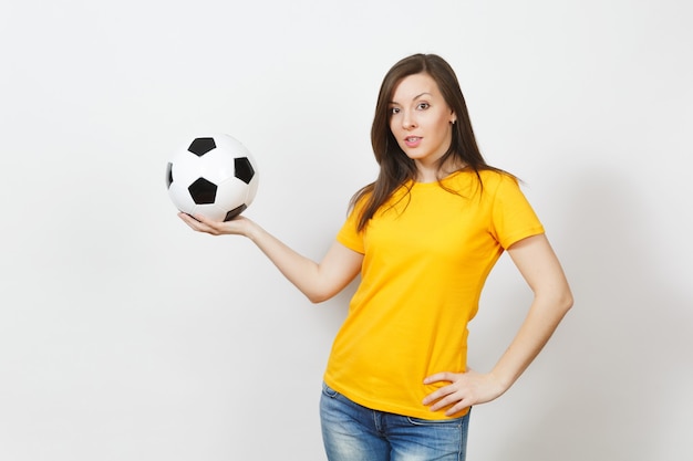 Beautiful european young cheerful happy woman, football fan or\
player in yellow uniform holding soccer ball isolated on white\
background. sport, play football, health, healthy lifestyle\
concept.