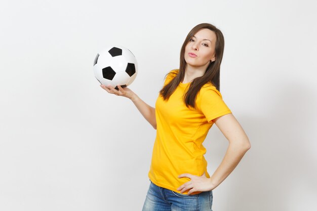 Beautiful european young cheerful happy woman, football fan or\
player in yellow uniform holding soccer ball isolated on white\
background. sport, play football, health, healthy lifestyle\
concept.